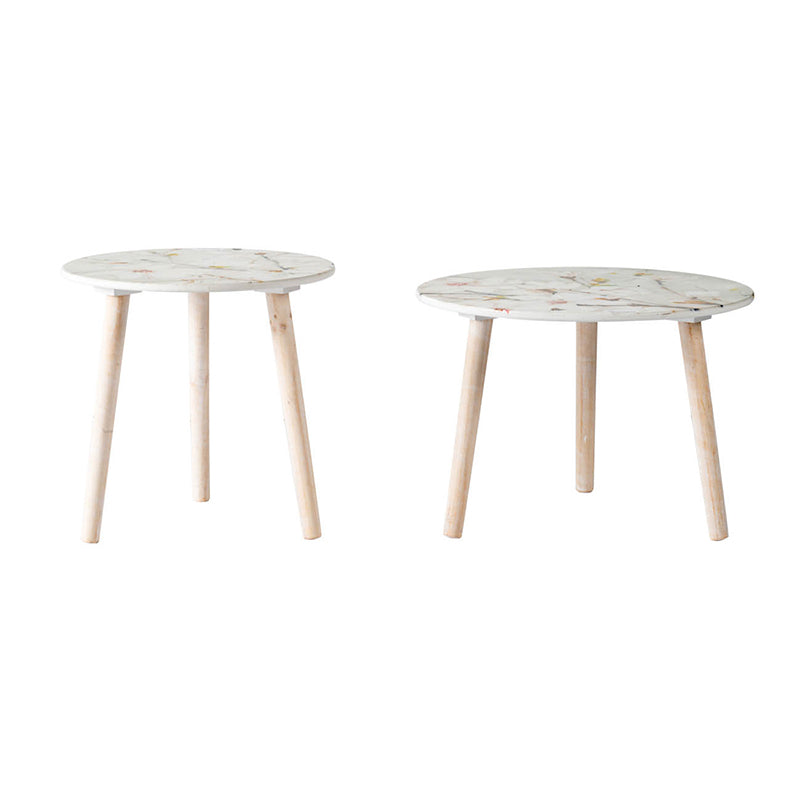 Two round side tables with white marblelike tops and light wood legs featuring delicate floral accents