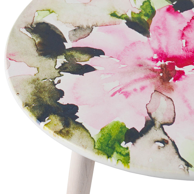 Round coffee table with pink floral watercolor art and light wood leg