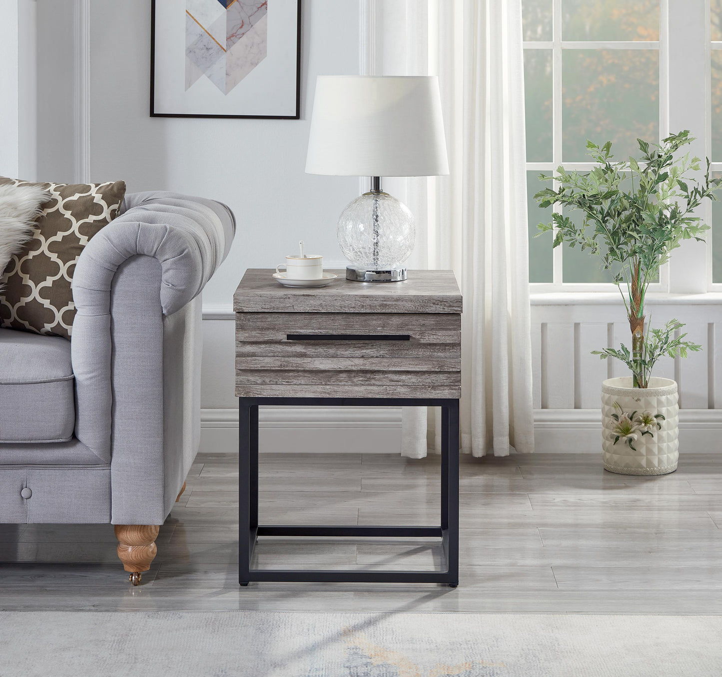 Gray wood grain end table with one drawer and black metal legs placed next to a sofa