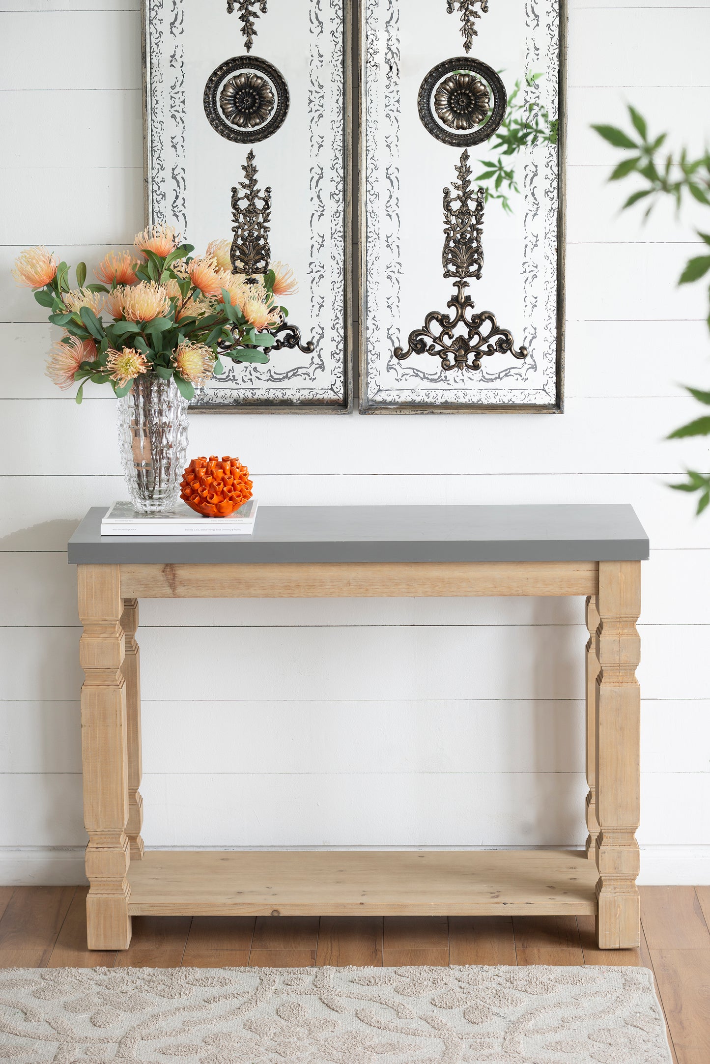 Rustic wood console table with gray top featuring ornate wall art and floral arrangement