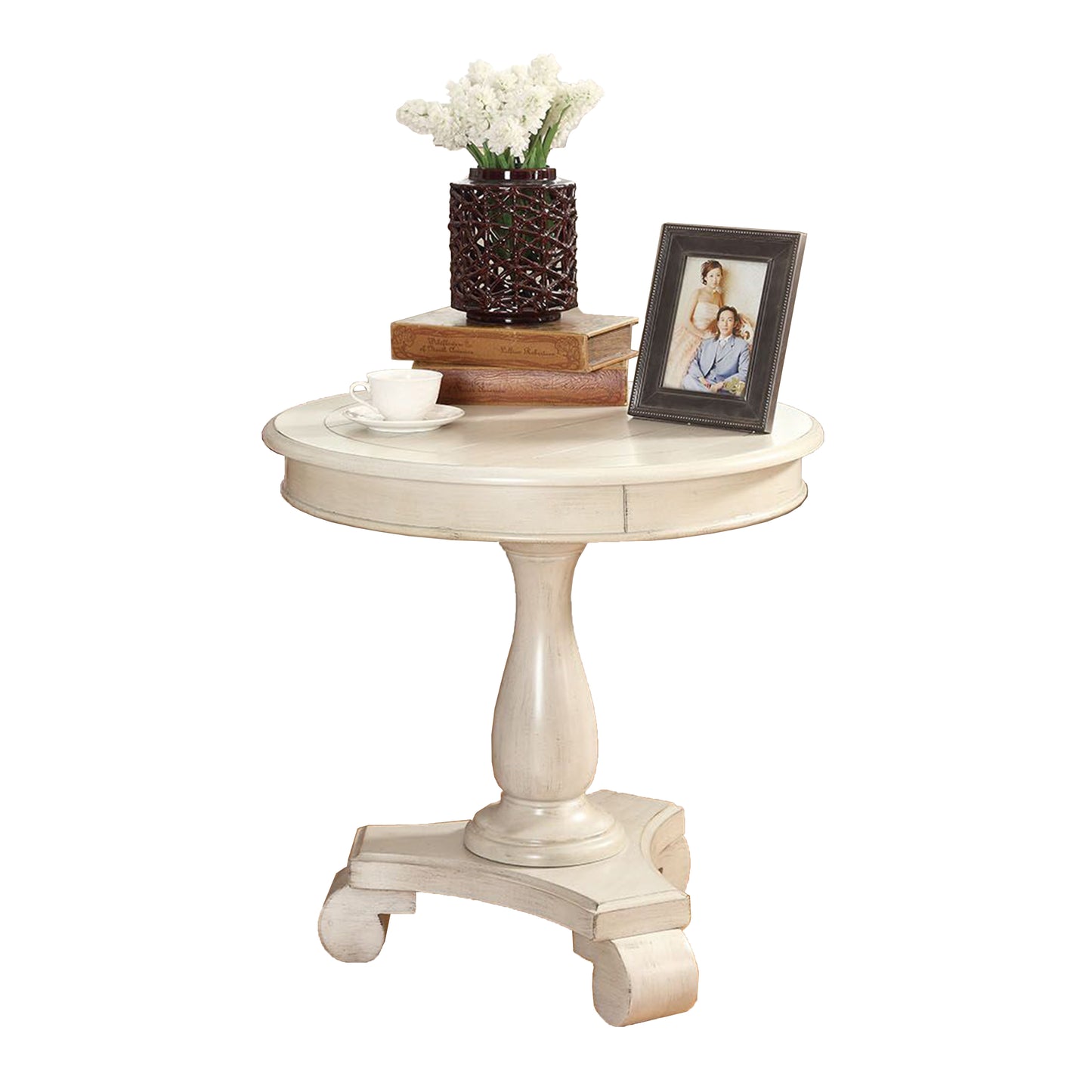 Elegant distressed white pedestal accent table with stacked books and white flowers