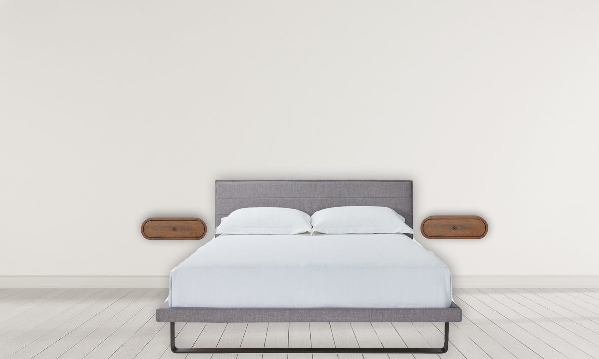Upholstered grey fabric platform bed with white linens and minimalist bedside tables