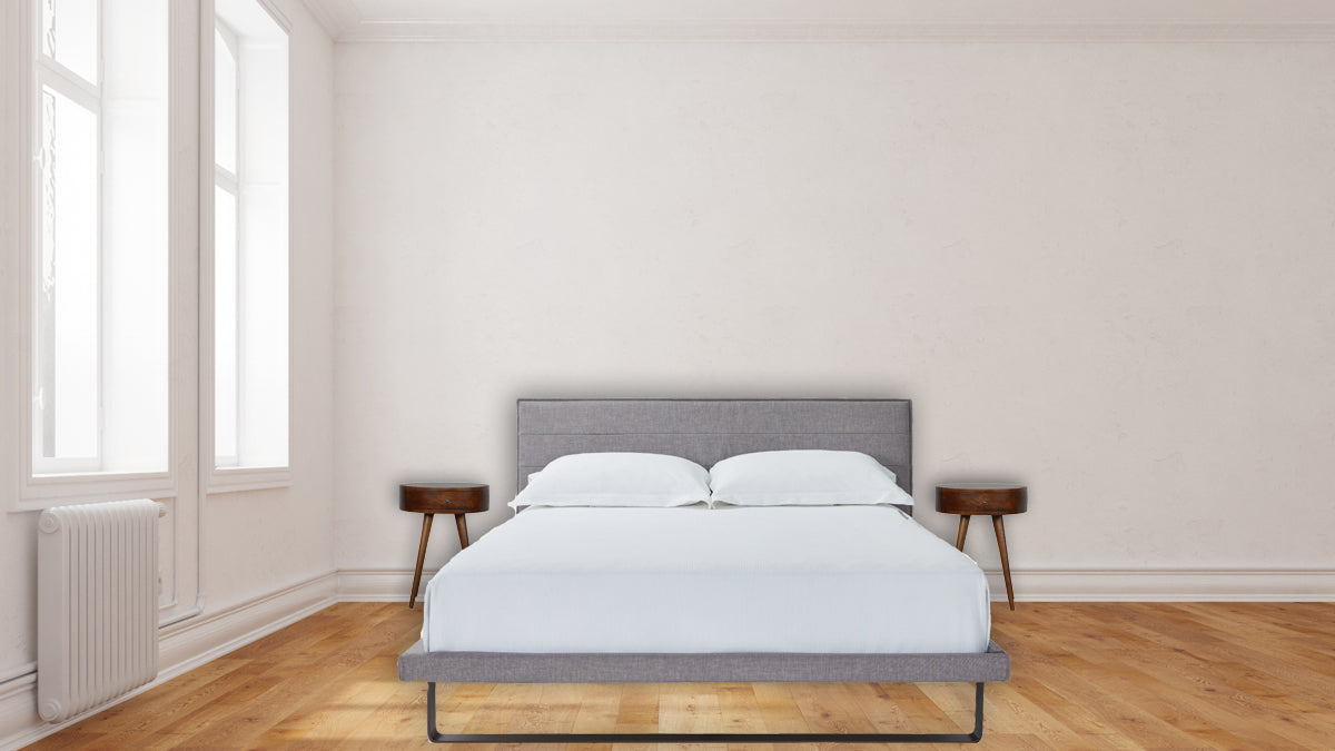 Gray upholstered platform bed with white linens and two nightstands