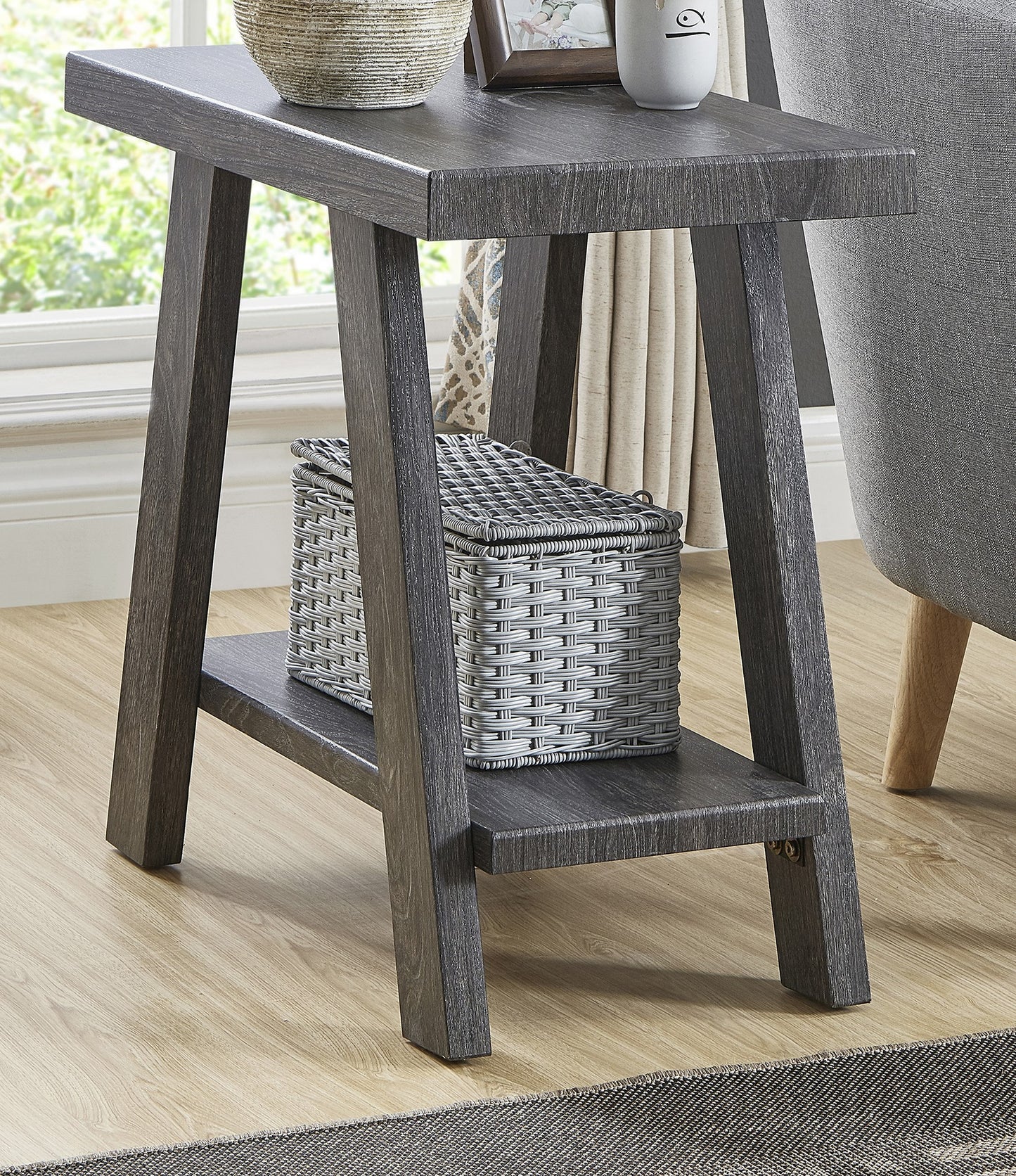 Rustic grey wooden side table with a woven storage basket on the lower shelf