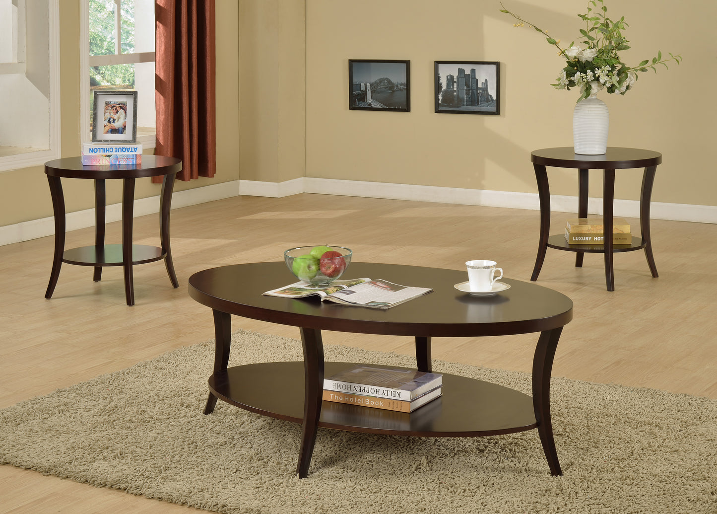 Dark wood oval coffee table with shelf holding books and fruit bowl