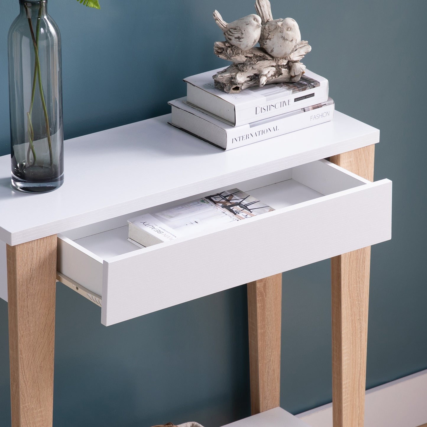 White and wood console table with open drawer and decorative items