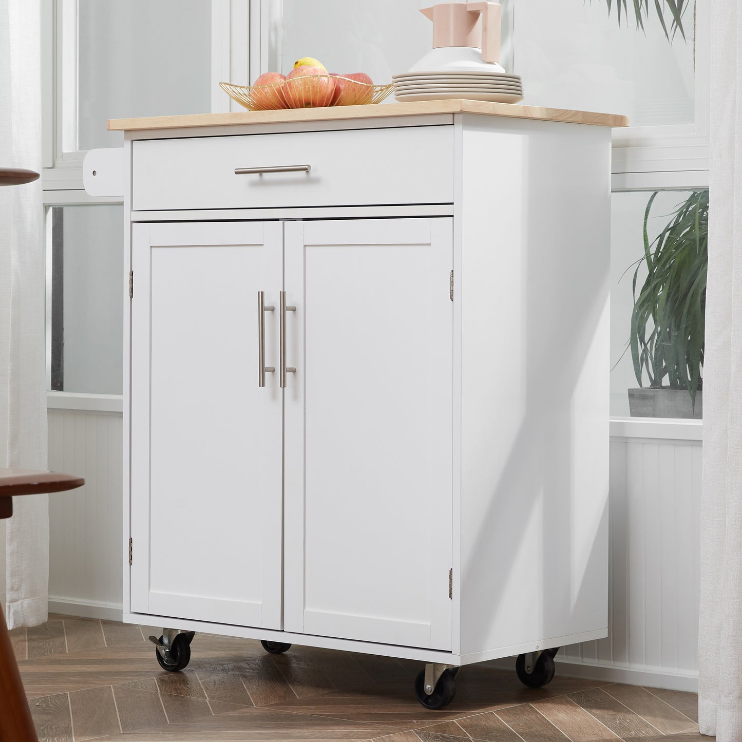 White kitchen cart with dual cabinet doors silver handles and a wooden top