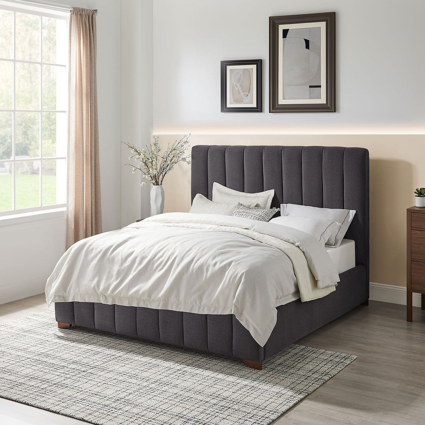 Dark grey upholstered platform bed with vertical channel tufting and plush bedding
