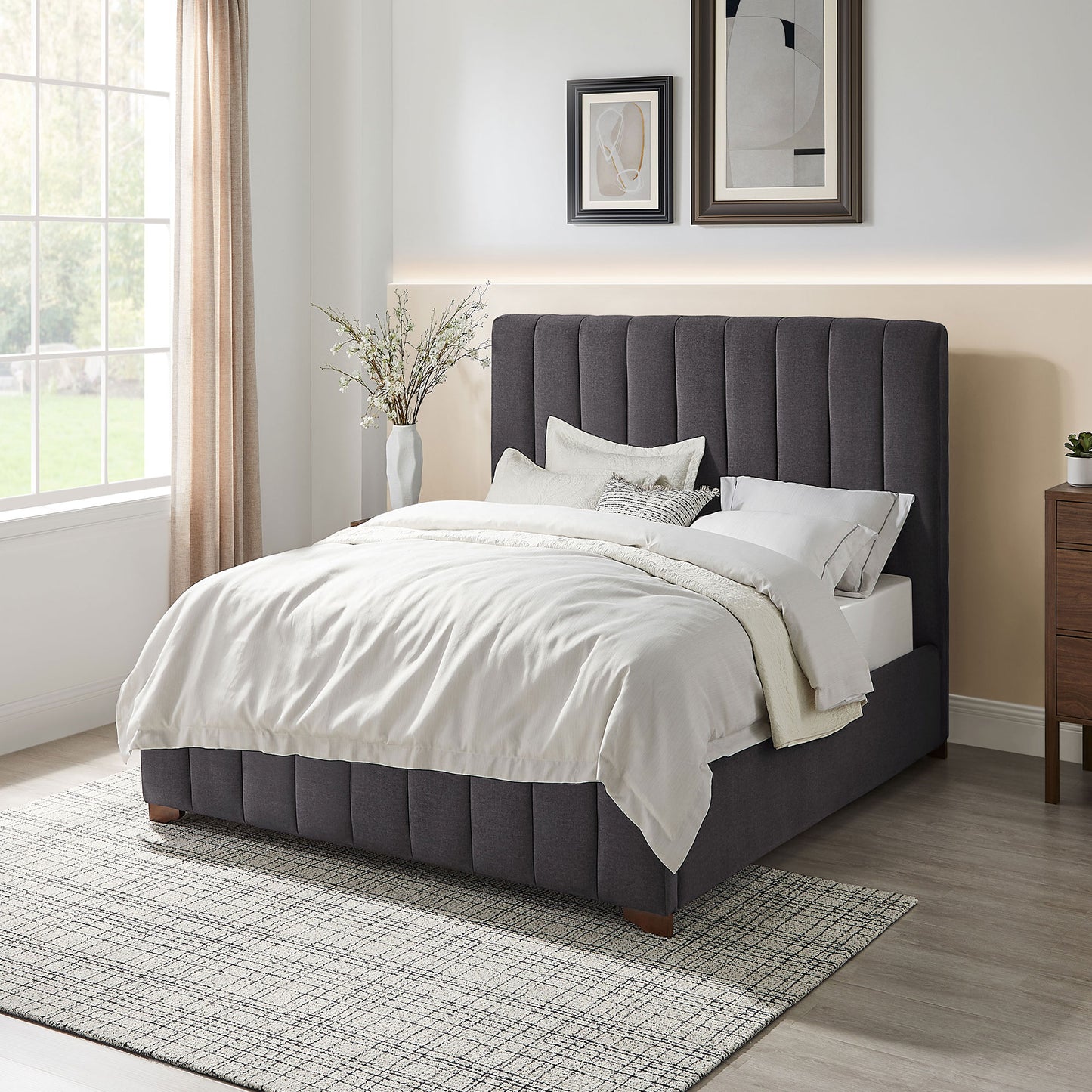 Dark grey upholstered king bed with vertical channel tufting and plush white bedding