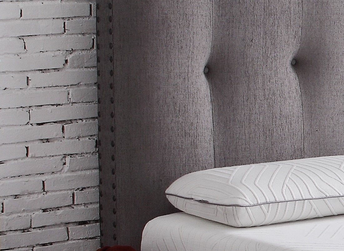 Gray upholstered headboard with tufted detail and studded trim