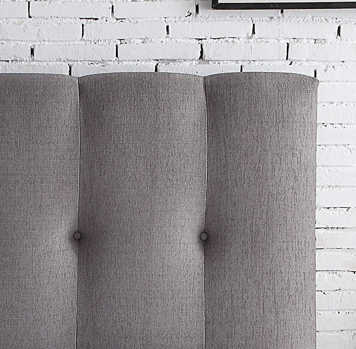 Closeup of gray upholstered headboard panels with tufted accents