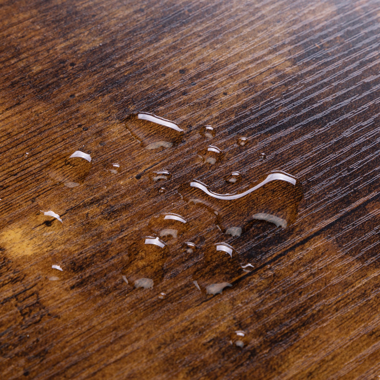 Dark brown wood grain surface with water droplets showcasing waterresistant finish
