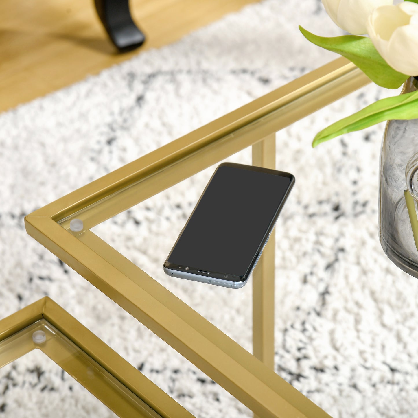 Gold metal frame coffee table with clear glass top and smartphone