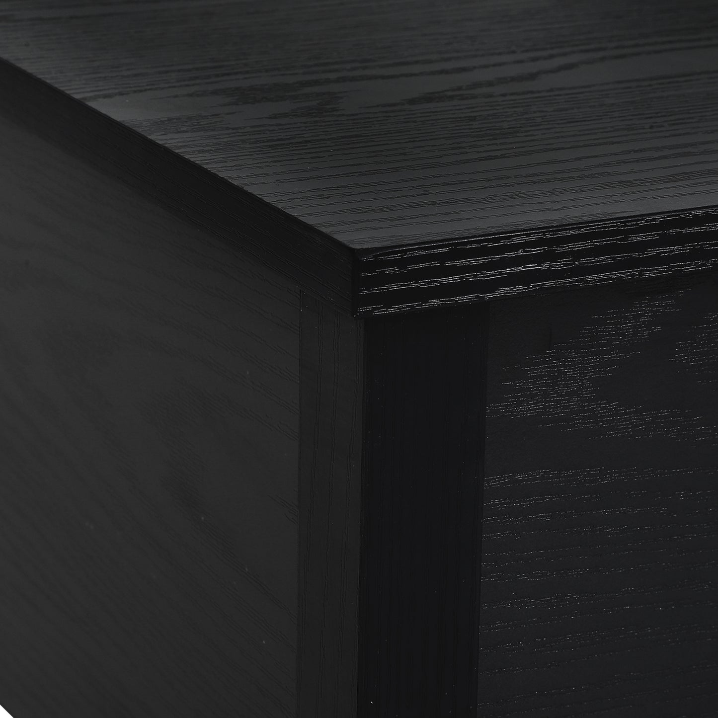 Closeup of a black wood veneer desk corner with visible grain texture