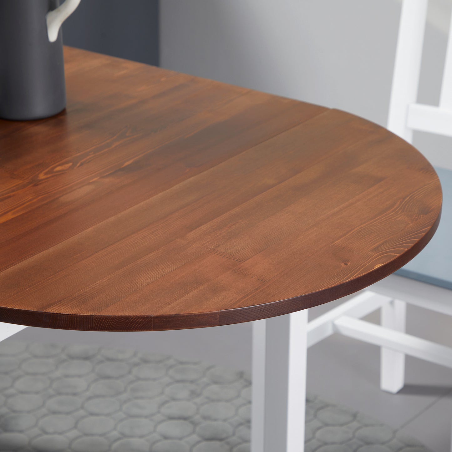 Round dining table with rich brown wood finish and white legs