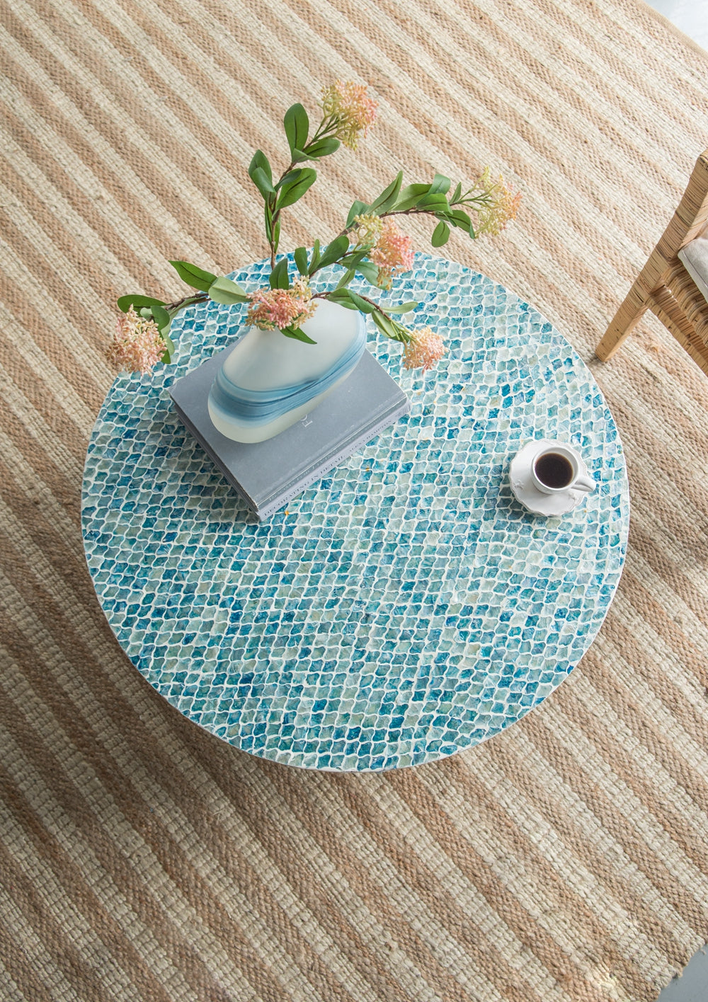 Blue mosaic round coffee table with floral arrangement and coffee cup