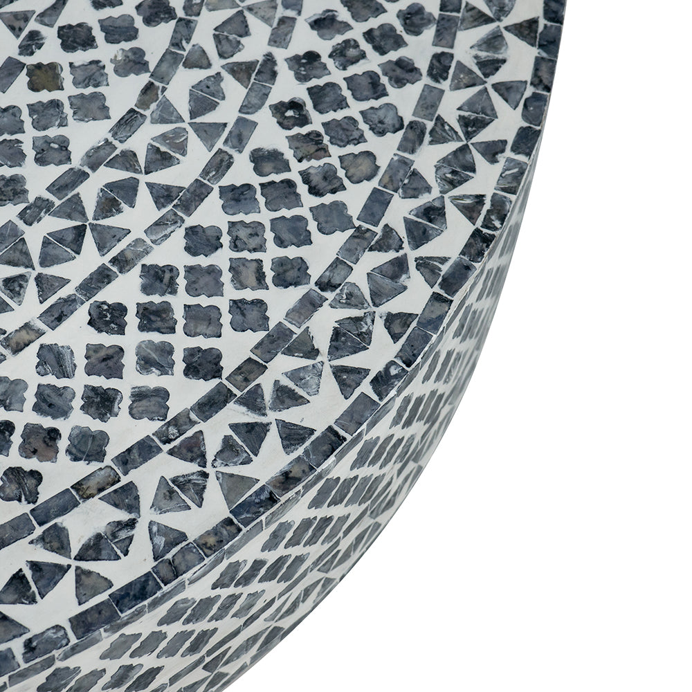 Closeup of a round side table with a geometric mosaic pattern in grey and white