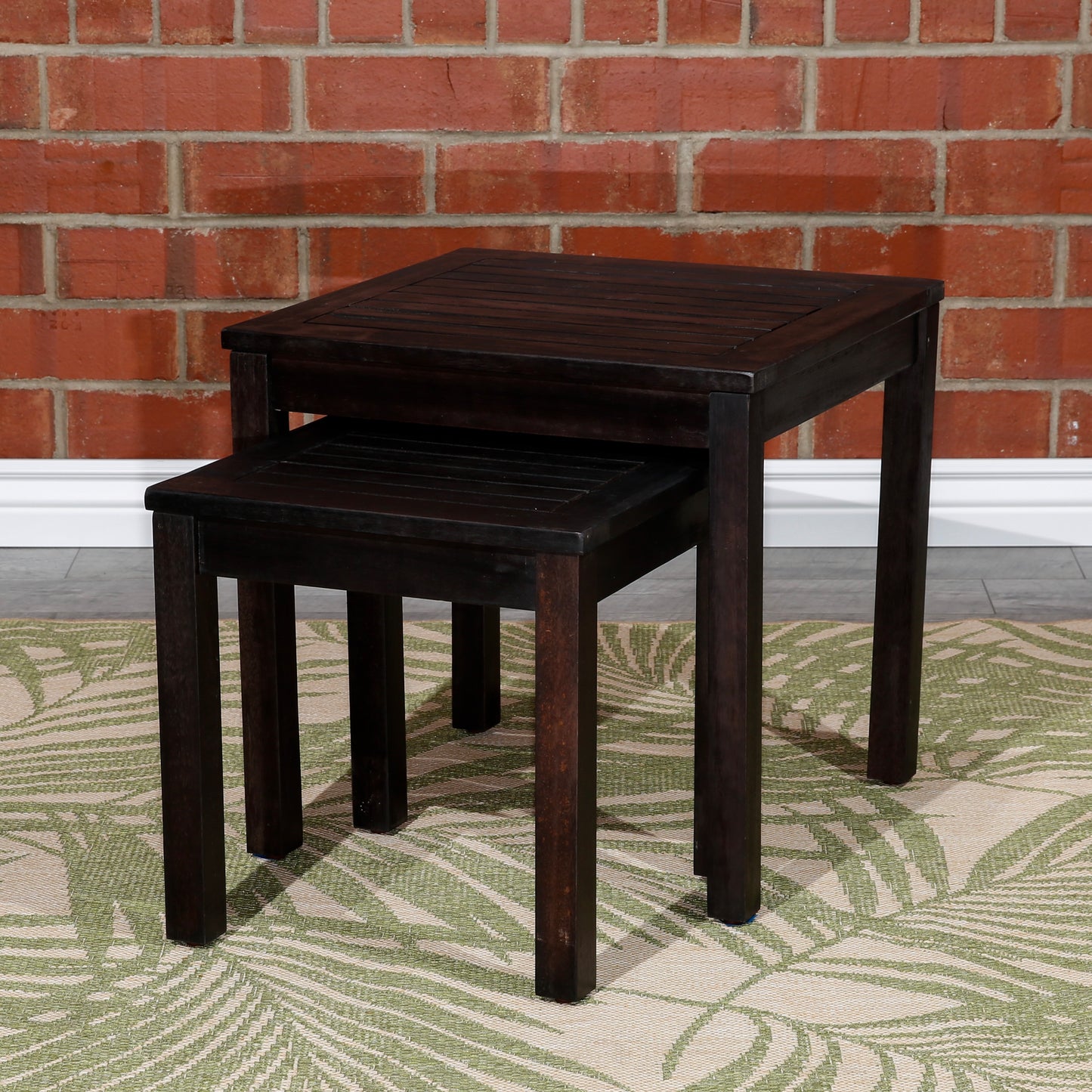 Dark wood nesting tables with slatted tops displayed on a tropical rug