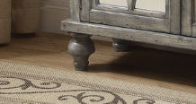 Distressed grey wooden cabinet legs on a patterned rug