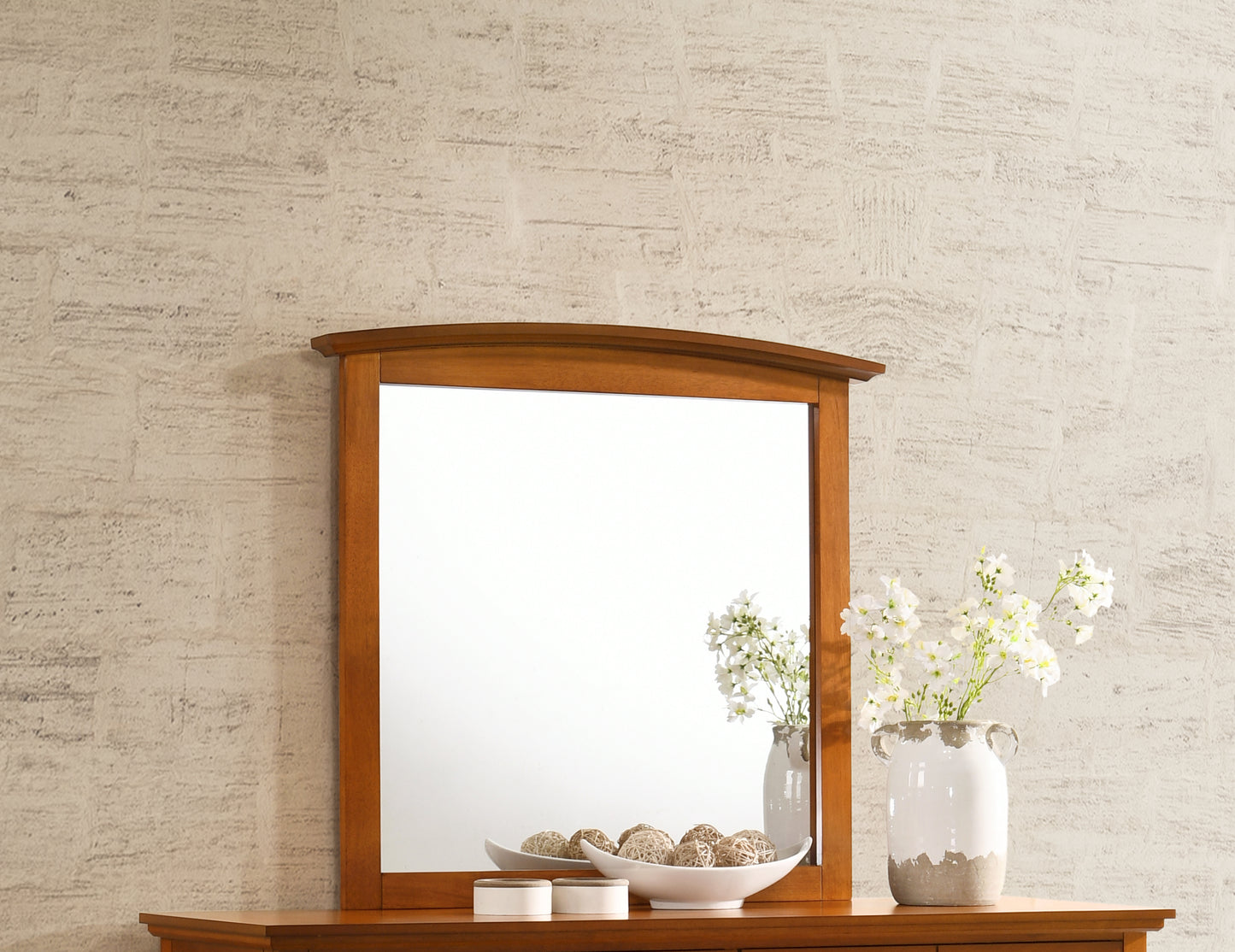 Wooden framed mirror with arched top and decorative vase with white flowers