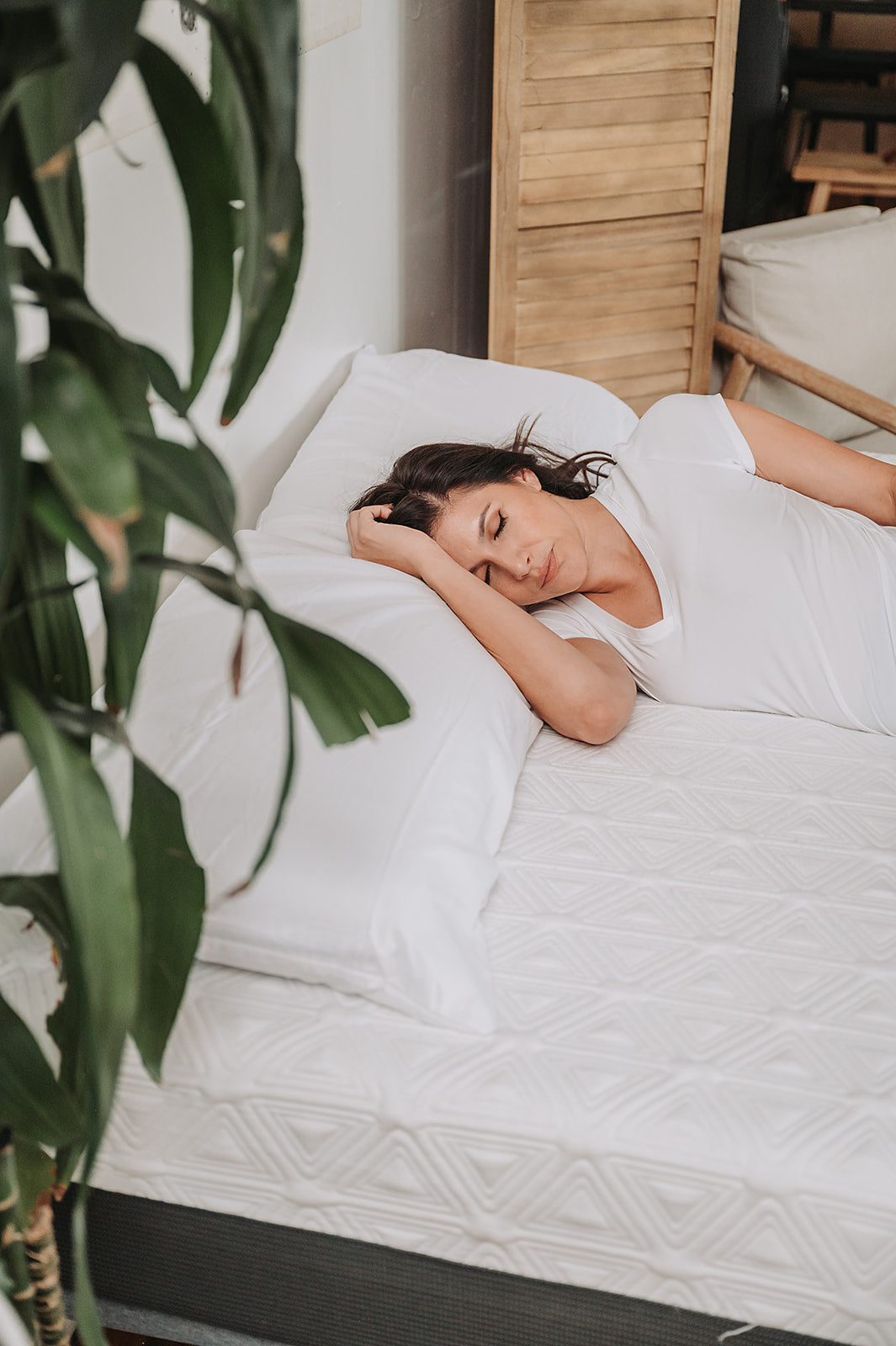 Woman sleeping on a luxurious white pillowtop mattress with geometric patterns