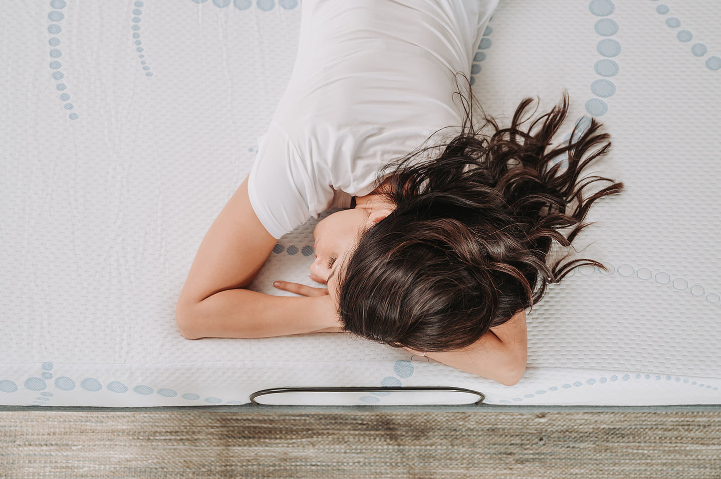 White mattress with blue circular pattern and woman resting comfortably
