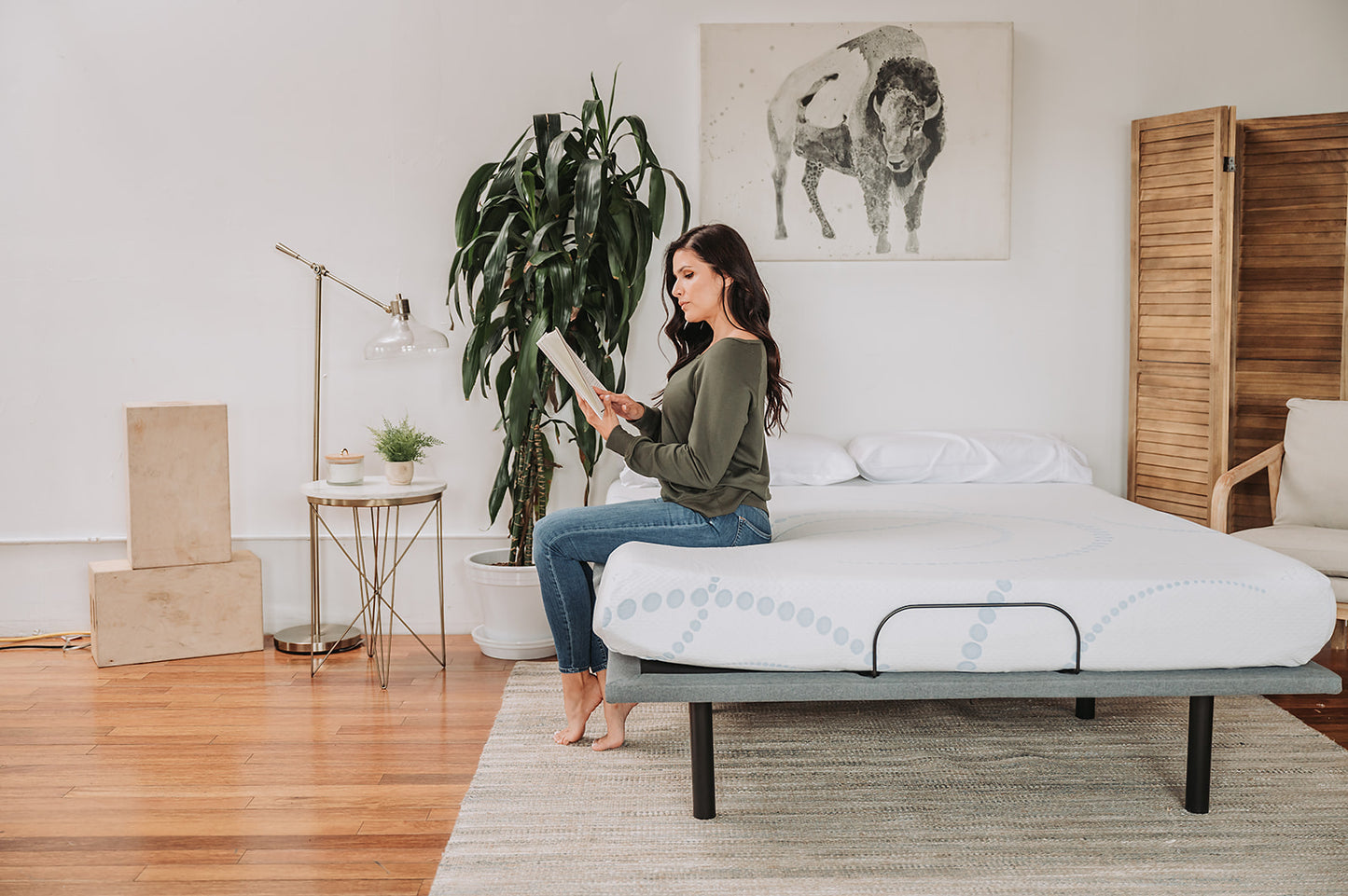 Woman reading on a white adjustable bed frame with a patterned mattress