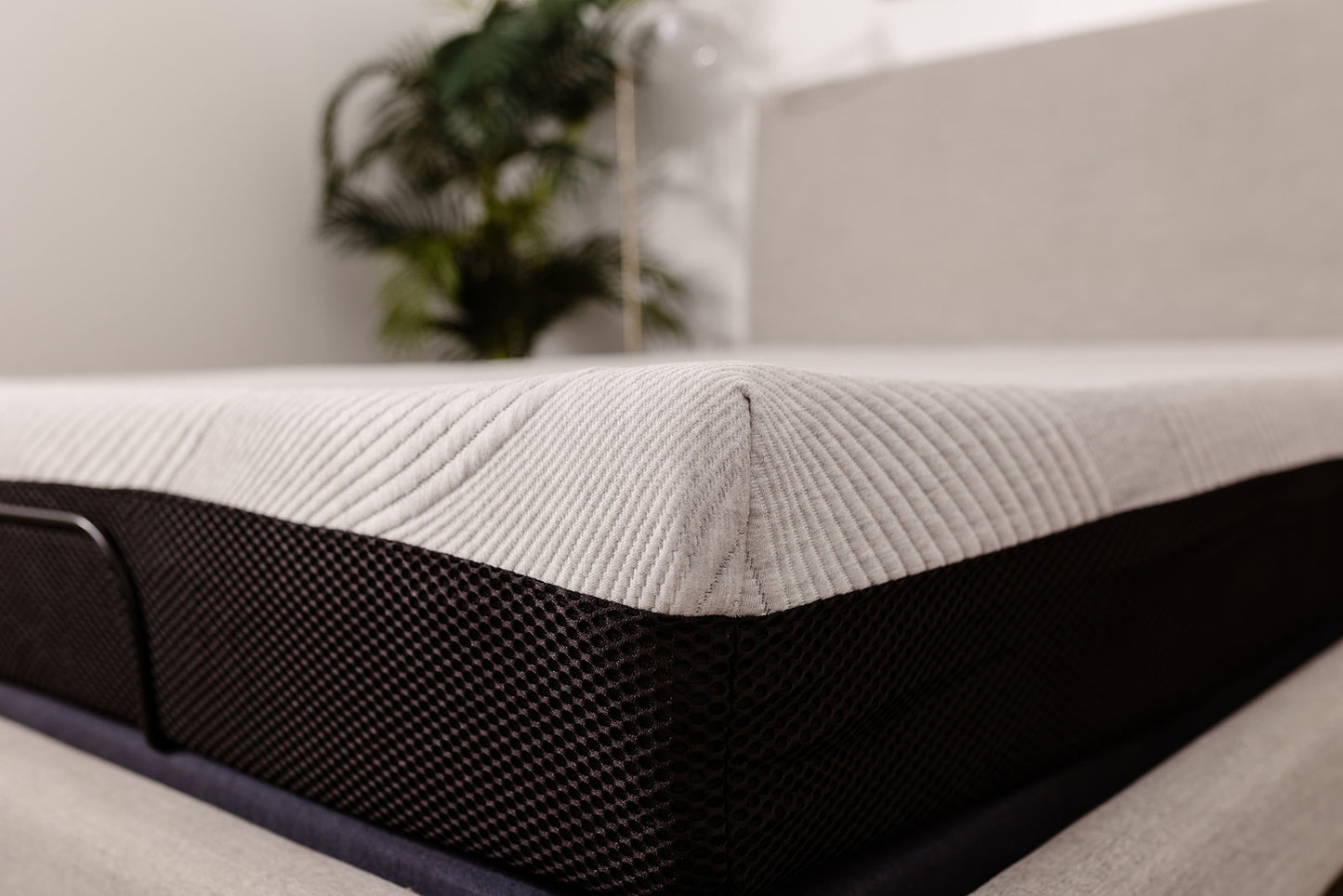 Closeup of a premium memory foam mattress with a ribbed gray top and black mesh sides