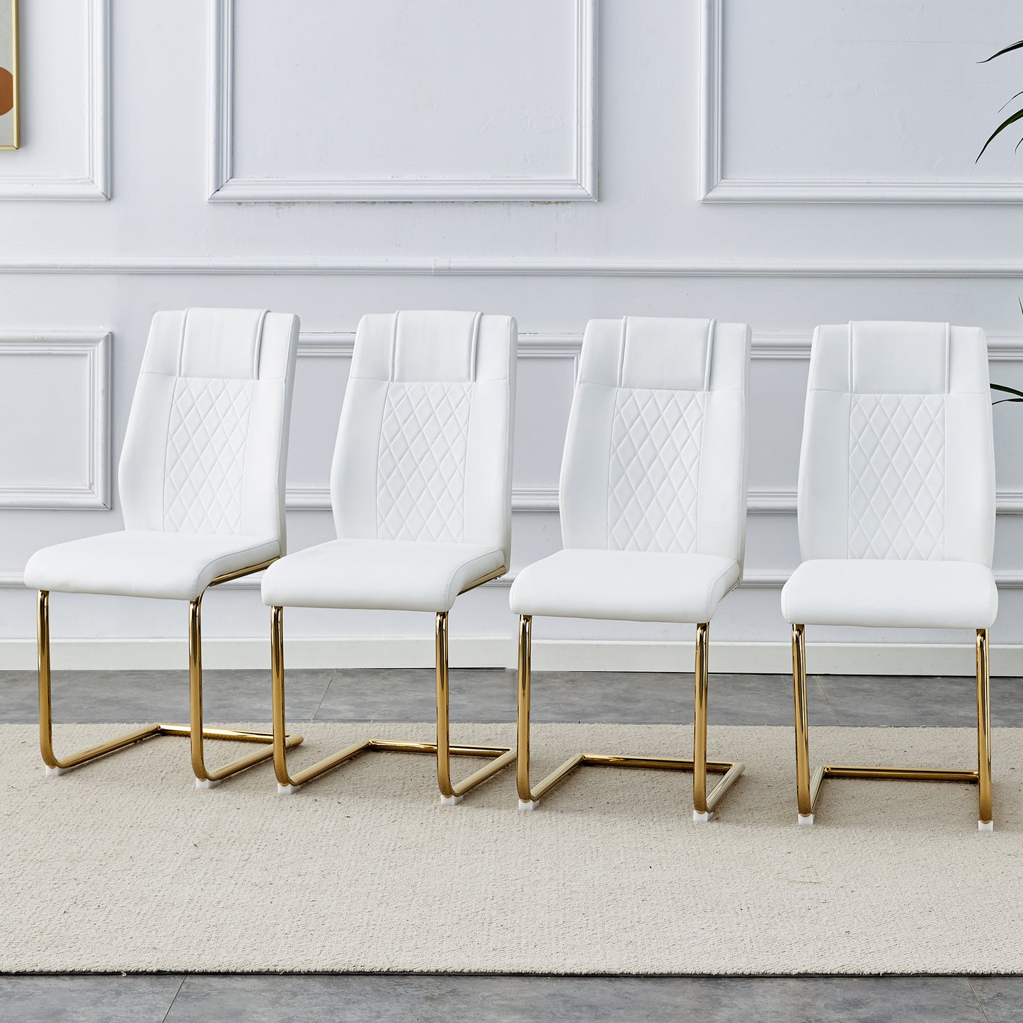 Four white dining chairs with diamondstitched backs and gold sled legs