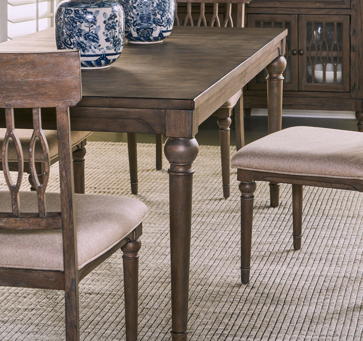 Dark wood dining table with turned legs and cushioned chairs