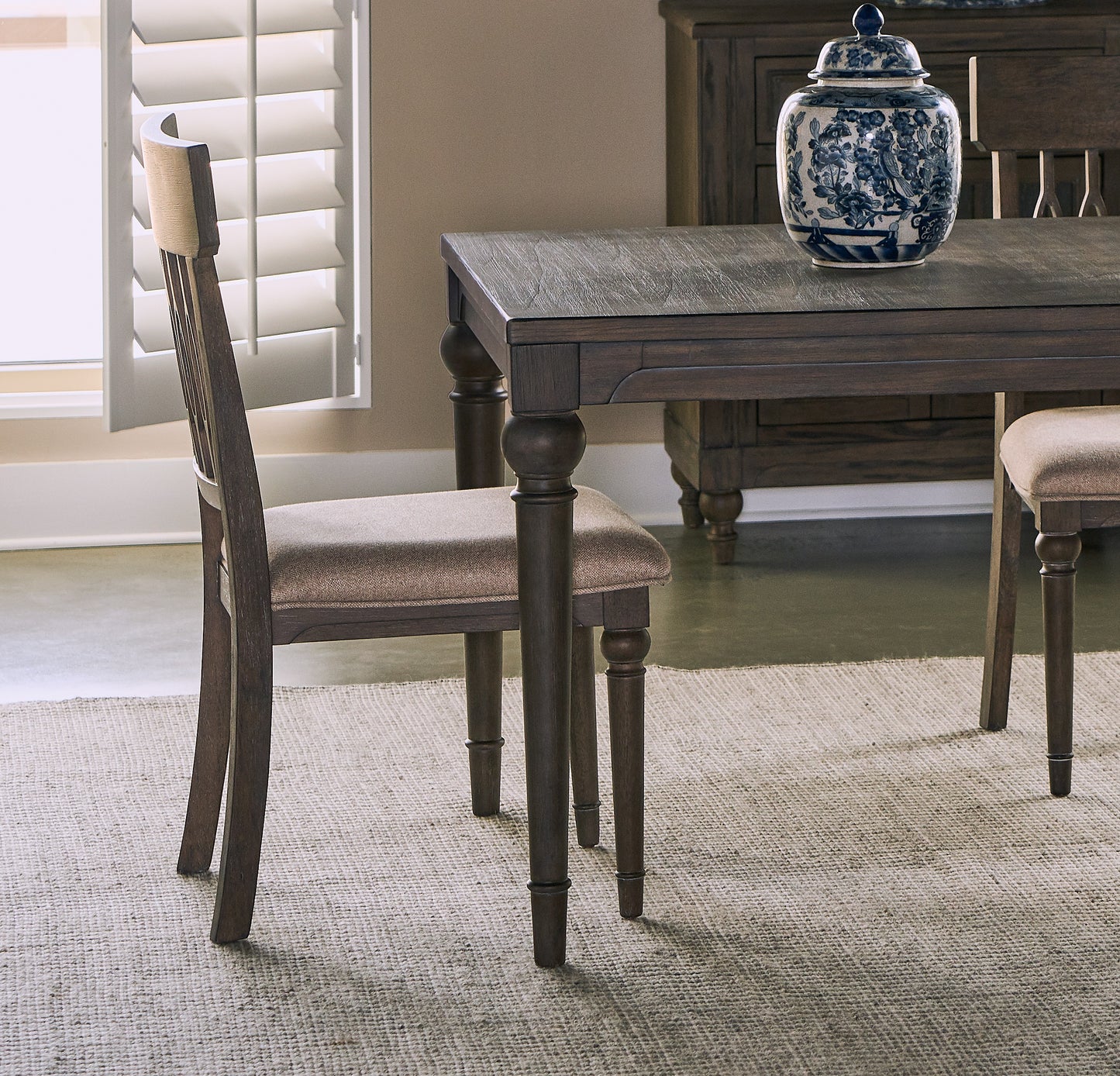 Dark wood dining chair with upholstered seat against white shutters