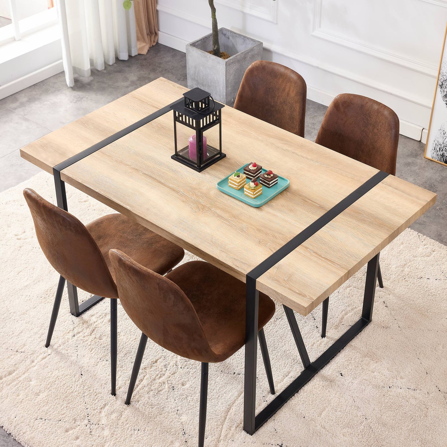 Light oak dining table with black metal accents and four brown faux leather chairs