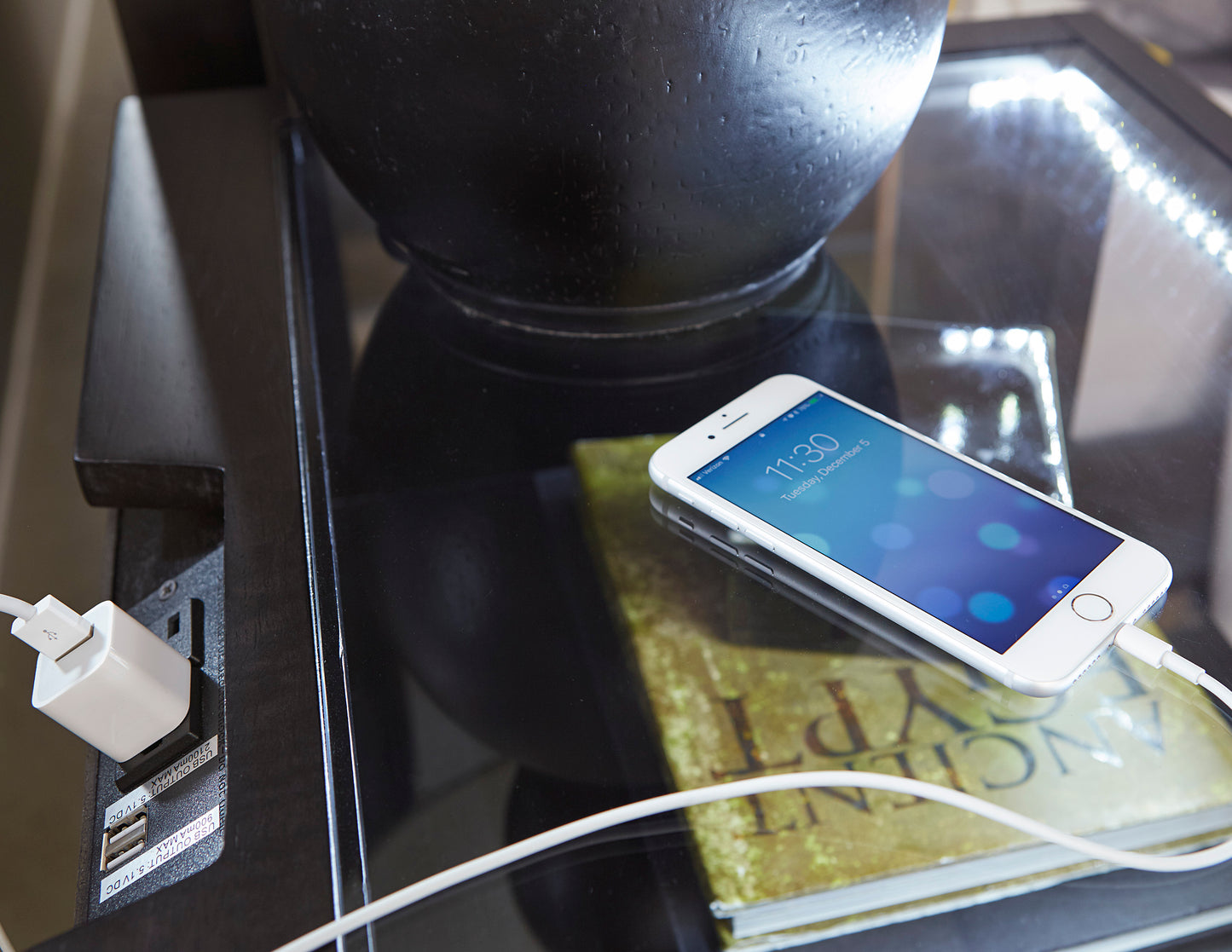 White iPhone s charging on a glass table