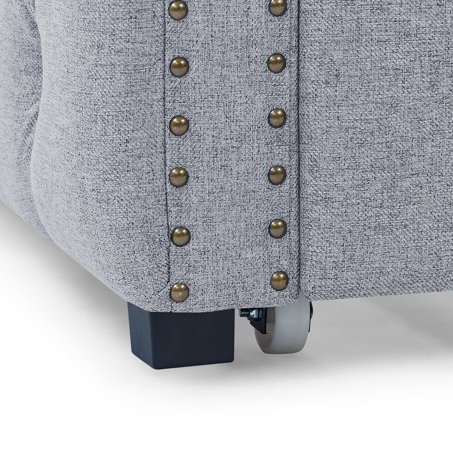 Closeup of grey textured fabric armchair with brass nailhead trim detail