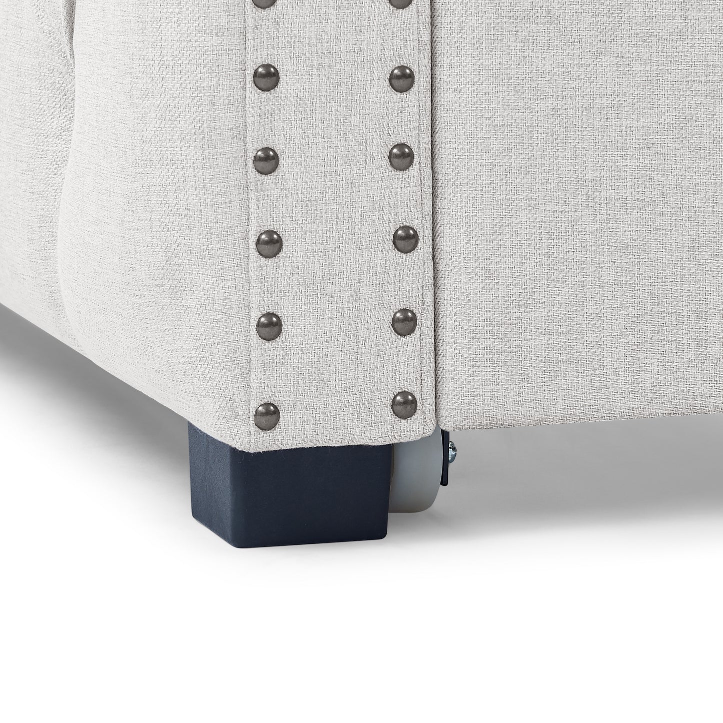 Closeup of light grey textured fabric sofa with studded trim and dark blue legs