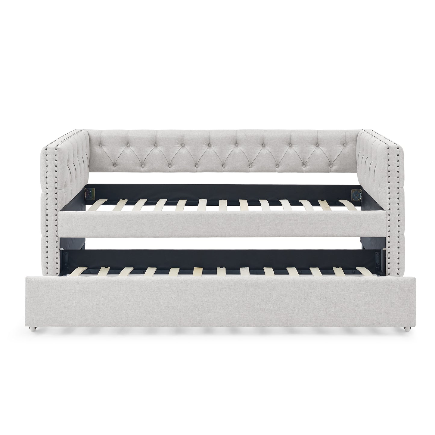 Light grey upholstered daybed with tufted back and nailhead trim featuring a pullout trundle