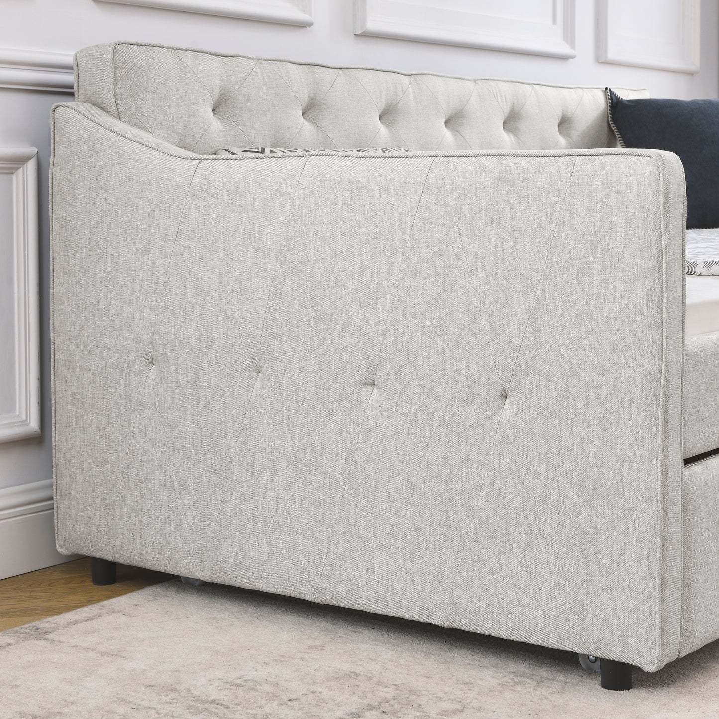 Light gray upholstered daybed with button tufting on the back and diamond stitching detail on the side panel