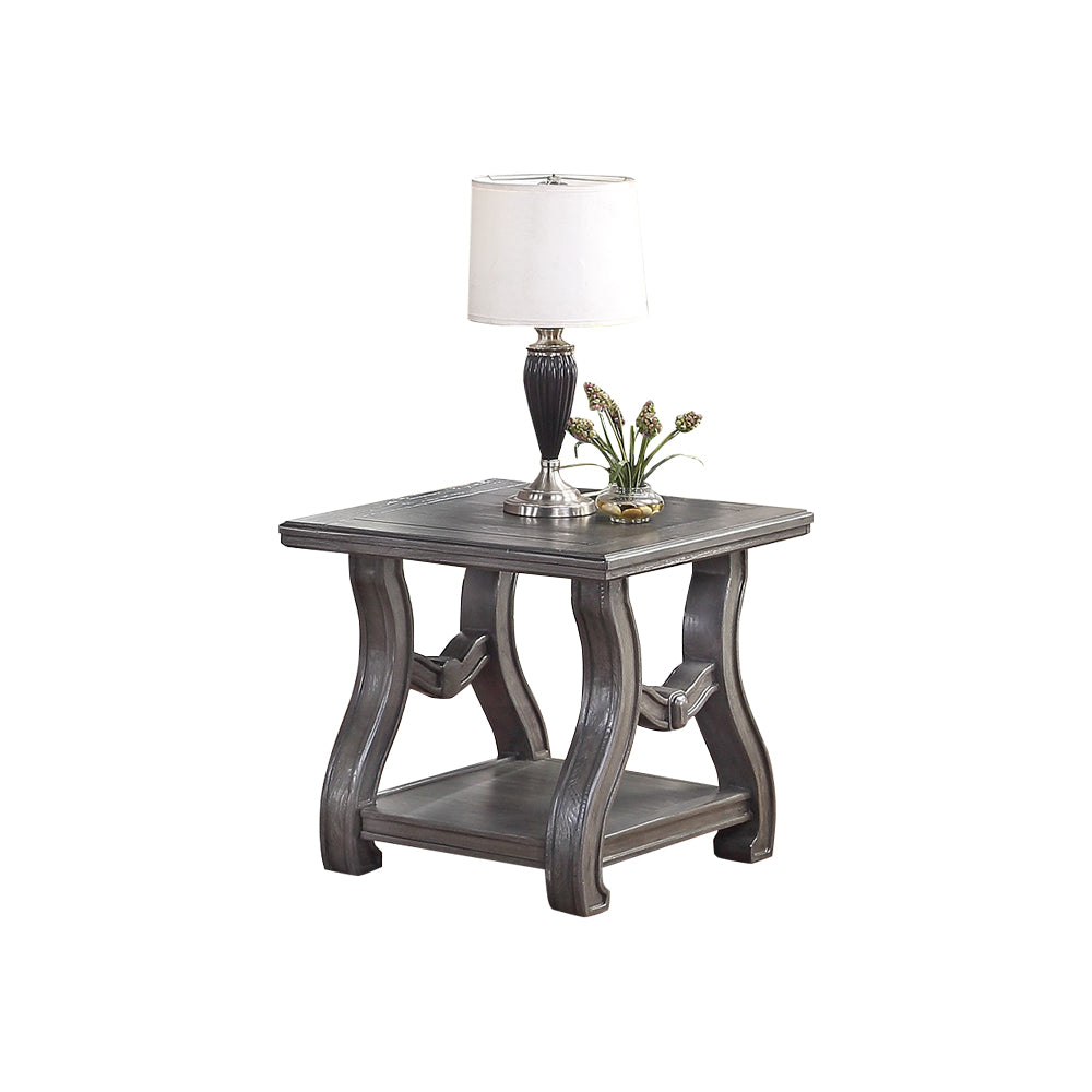 Ornate grey wood end table with carved legs and lower shelf holding a lamp