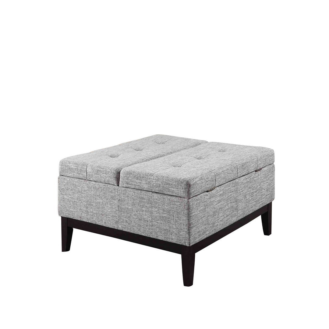 Gray tufted storage ottoman with dark wood legs providing hidden seating and footrest