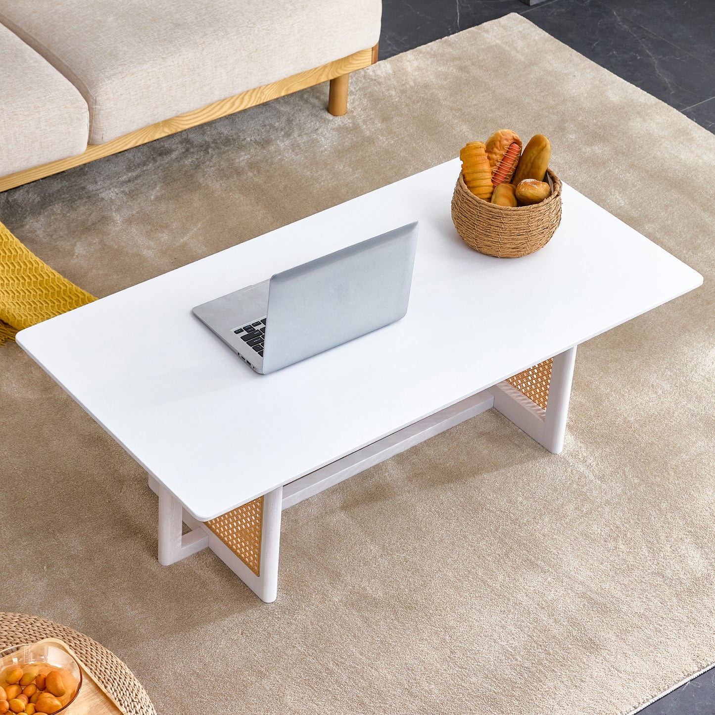 Modern white coffee table with rattan accents and a laptop