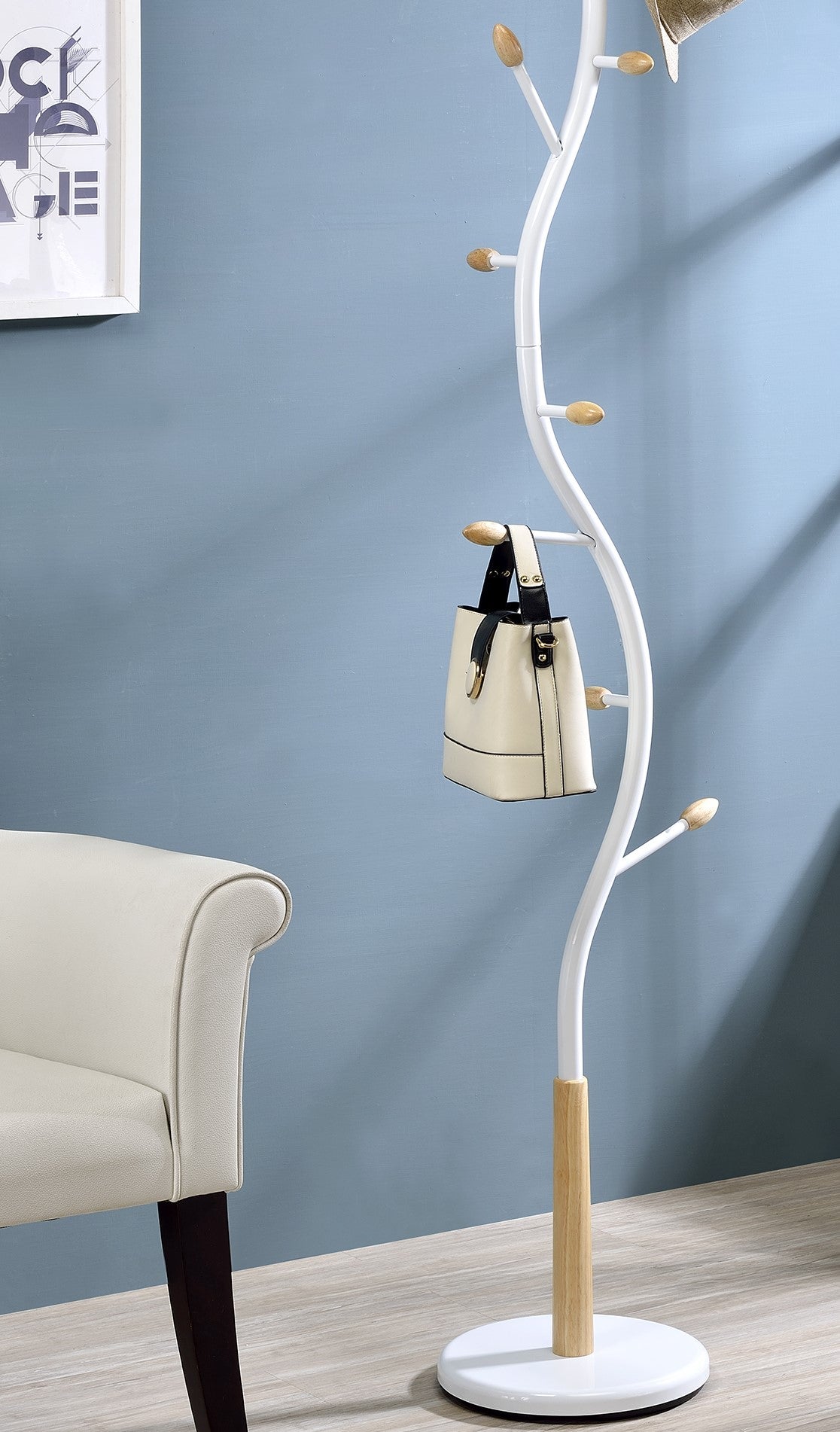 Modern white entryway coat rack with wood accents and a cream handbag