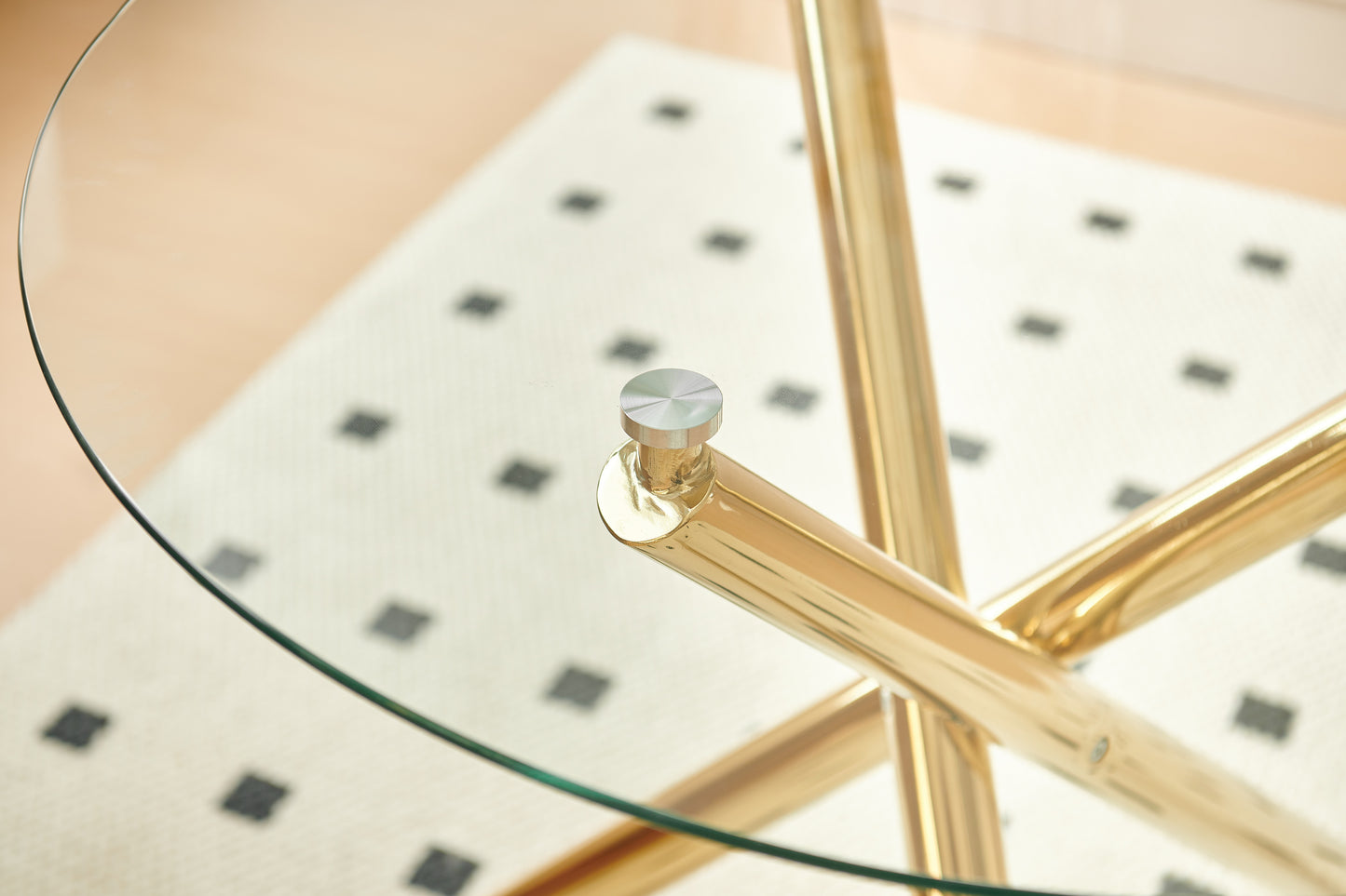 Closeup of a round glass coffee table with polished gold metal legs