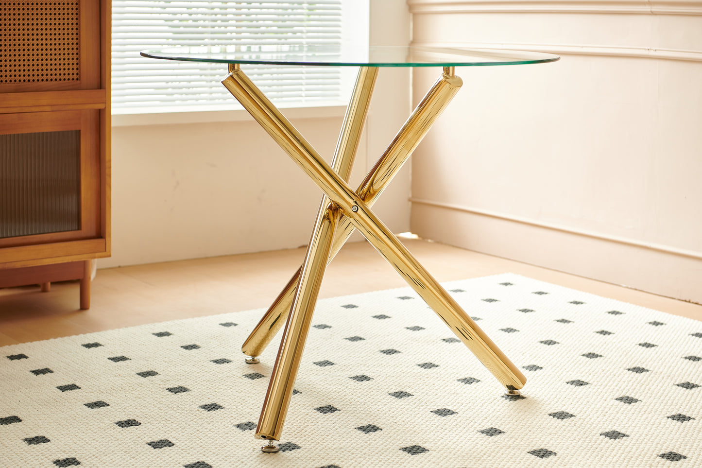 Round glass top coffee table with a polished gold Xshaped base