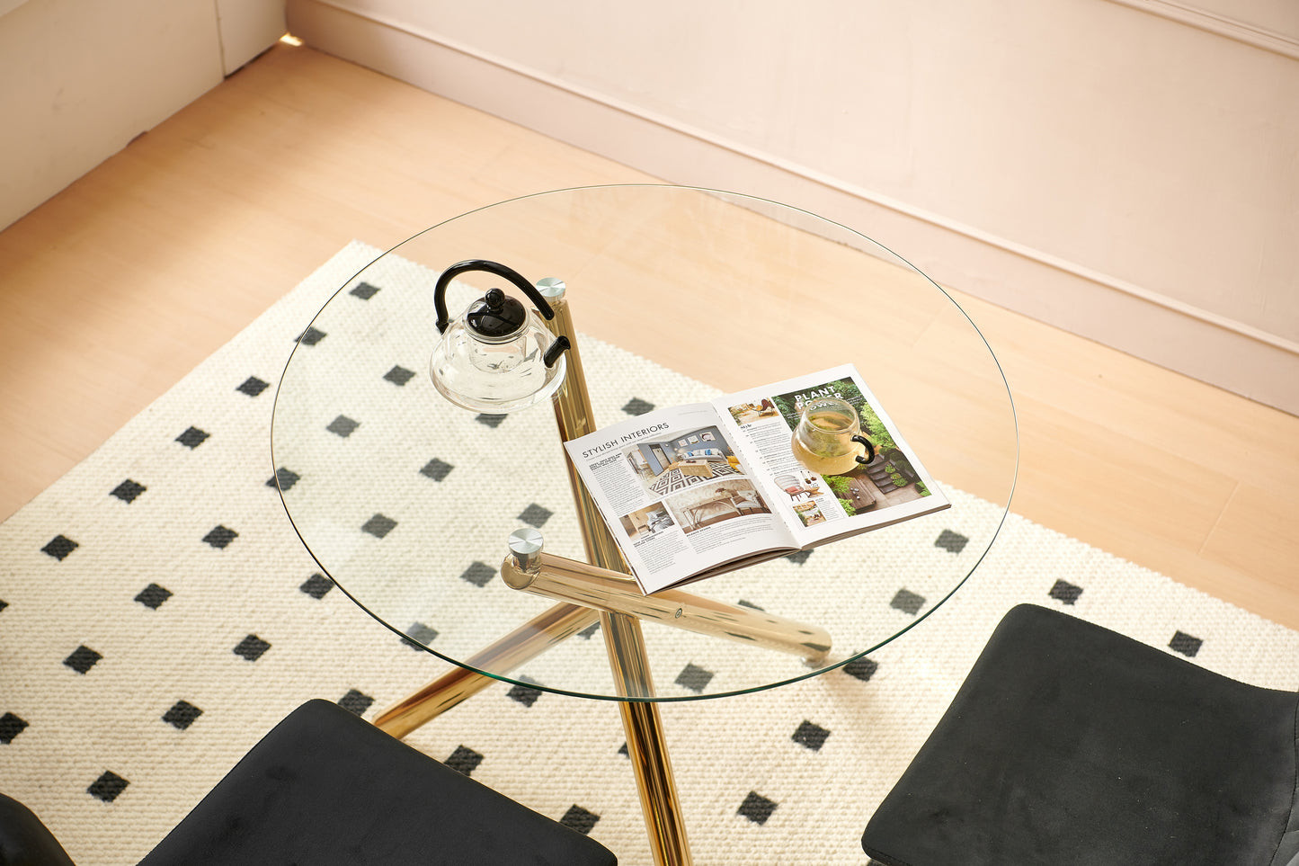 Clear glass kettle with black lid on a round glass coffee table