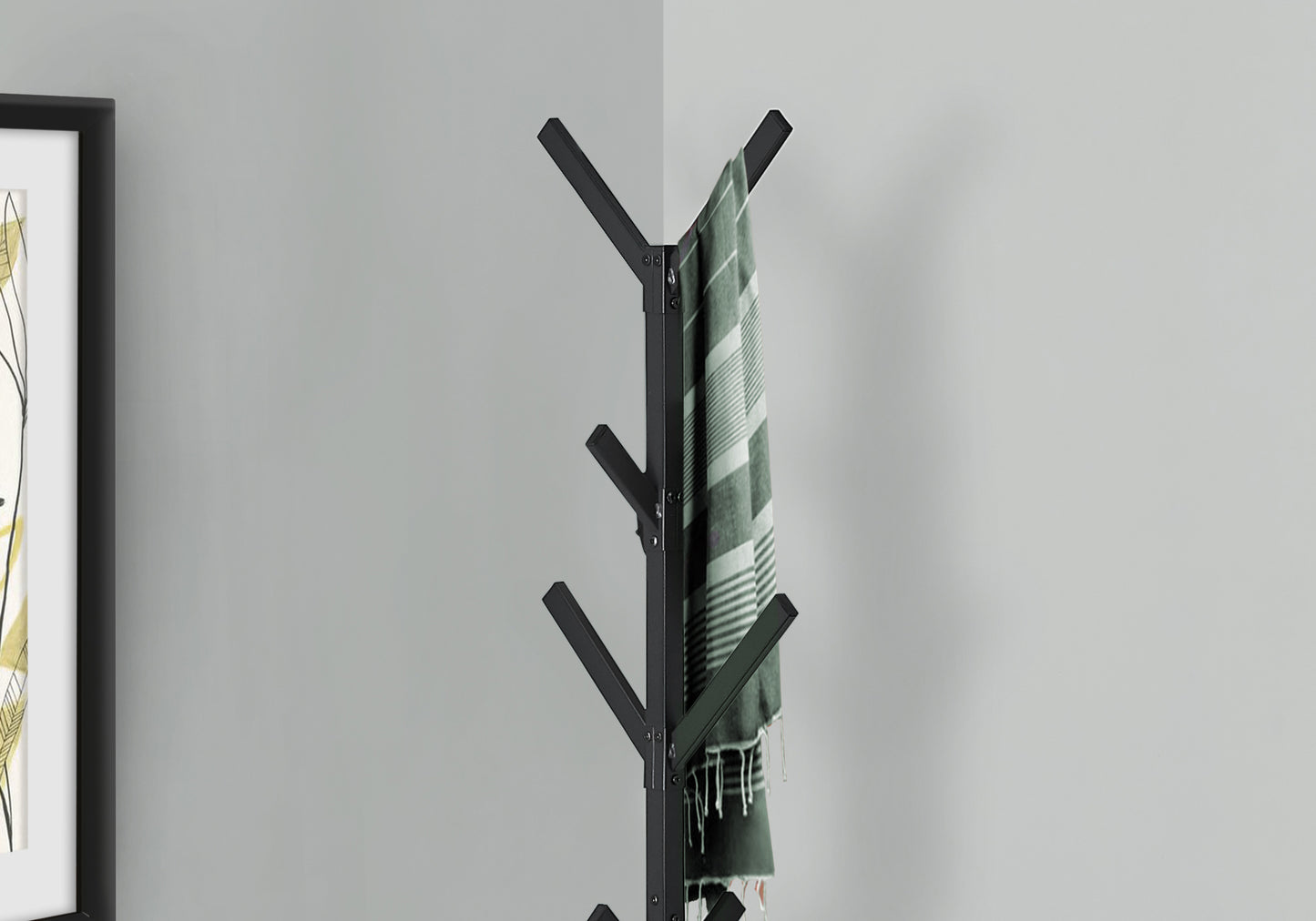 Black metal coat rack with hanging green striped scarf