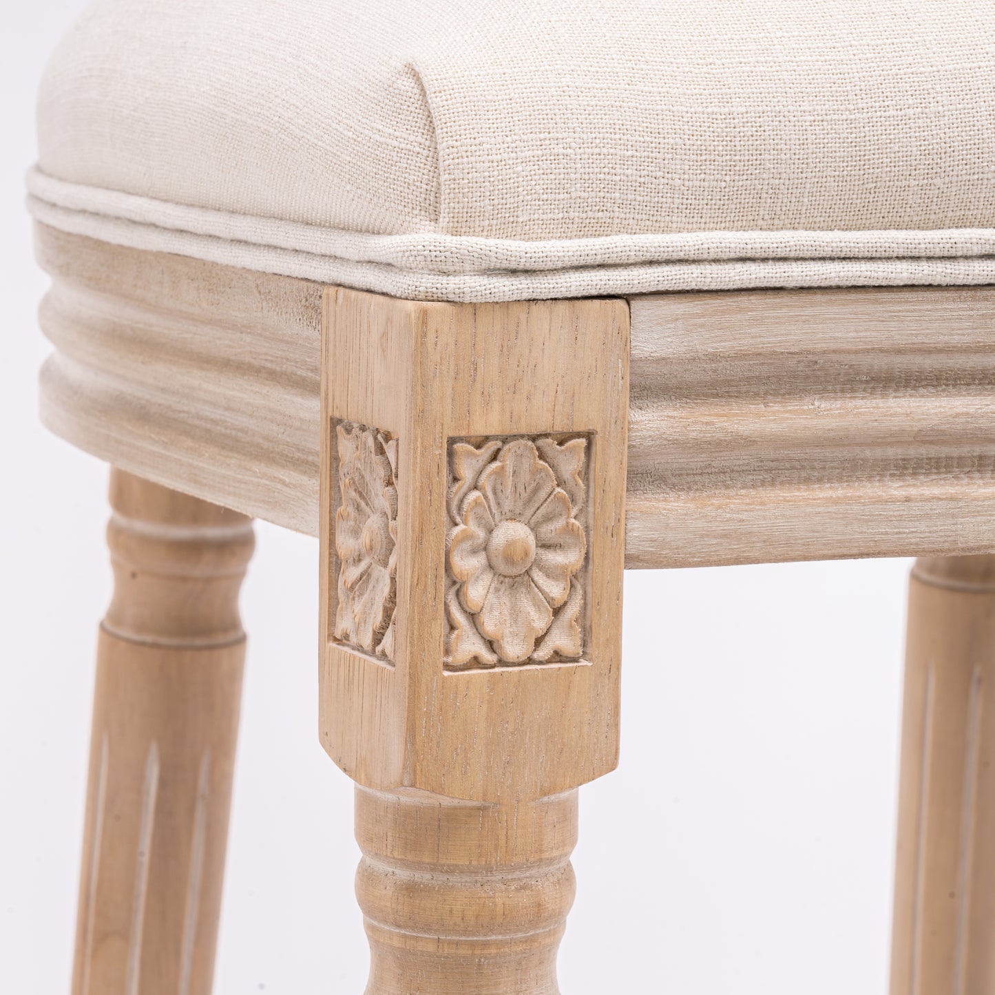 Beige upholstered stool with carved wooden legs and a distressed finish