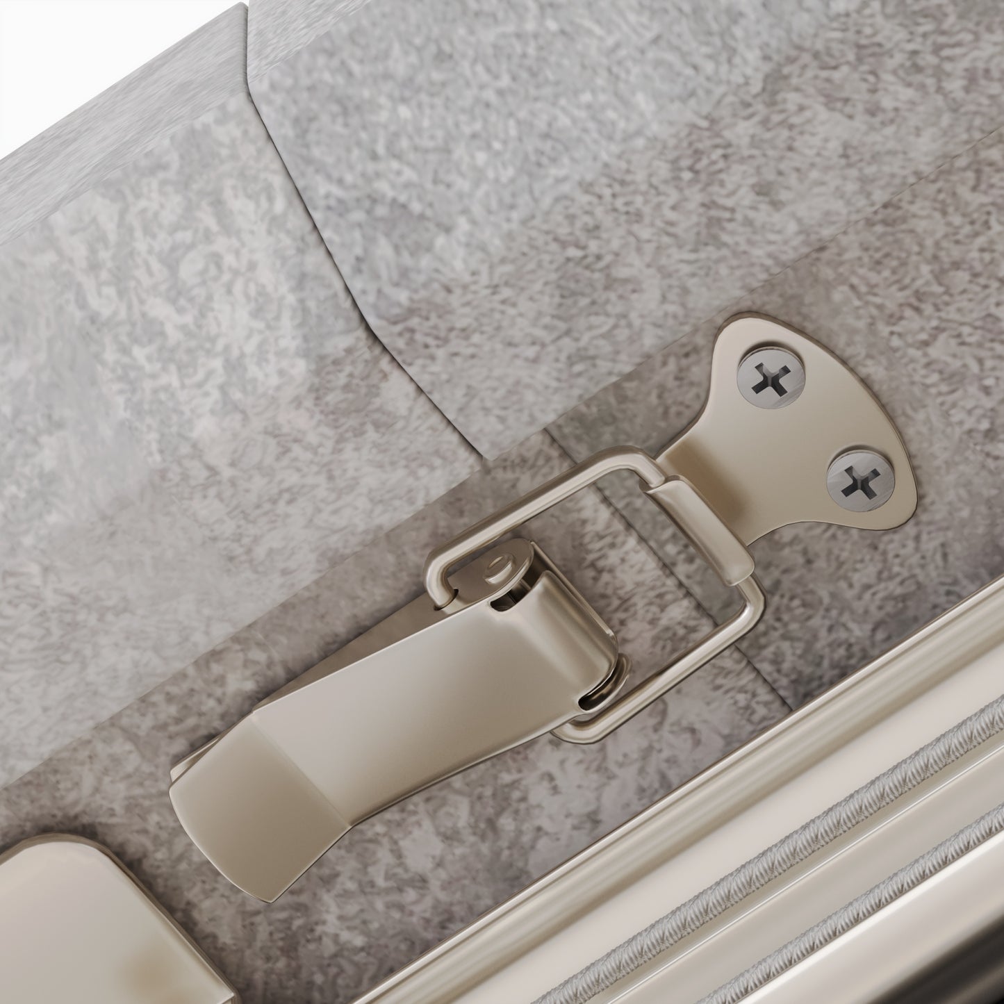 Brushed nickel suitcase latch with silver screws on a gray textured surface