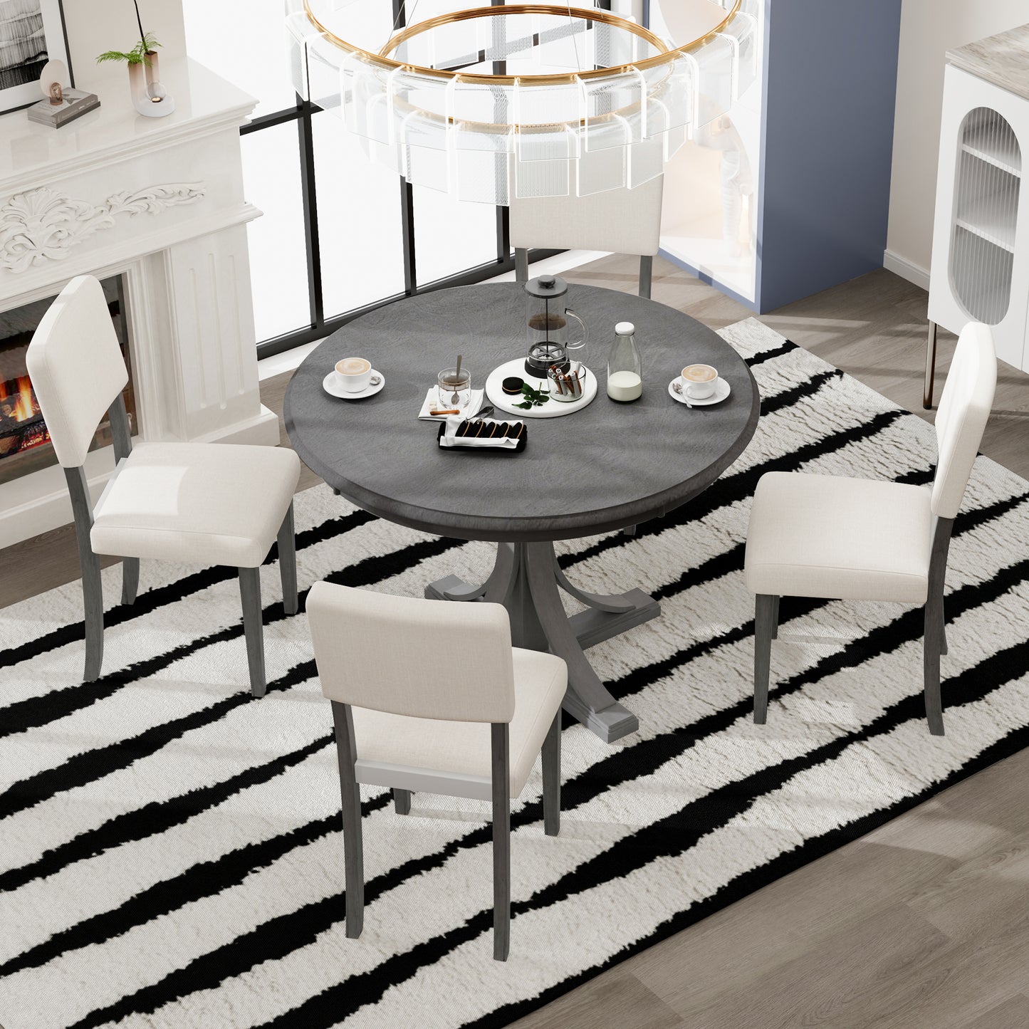 Round gray pedestal dining table with four cream upholstered chairs