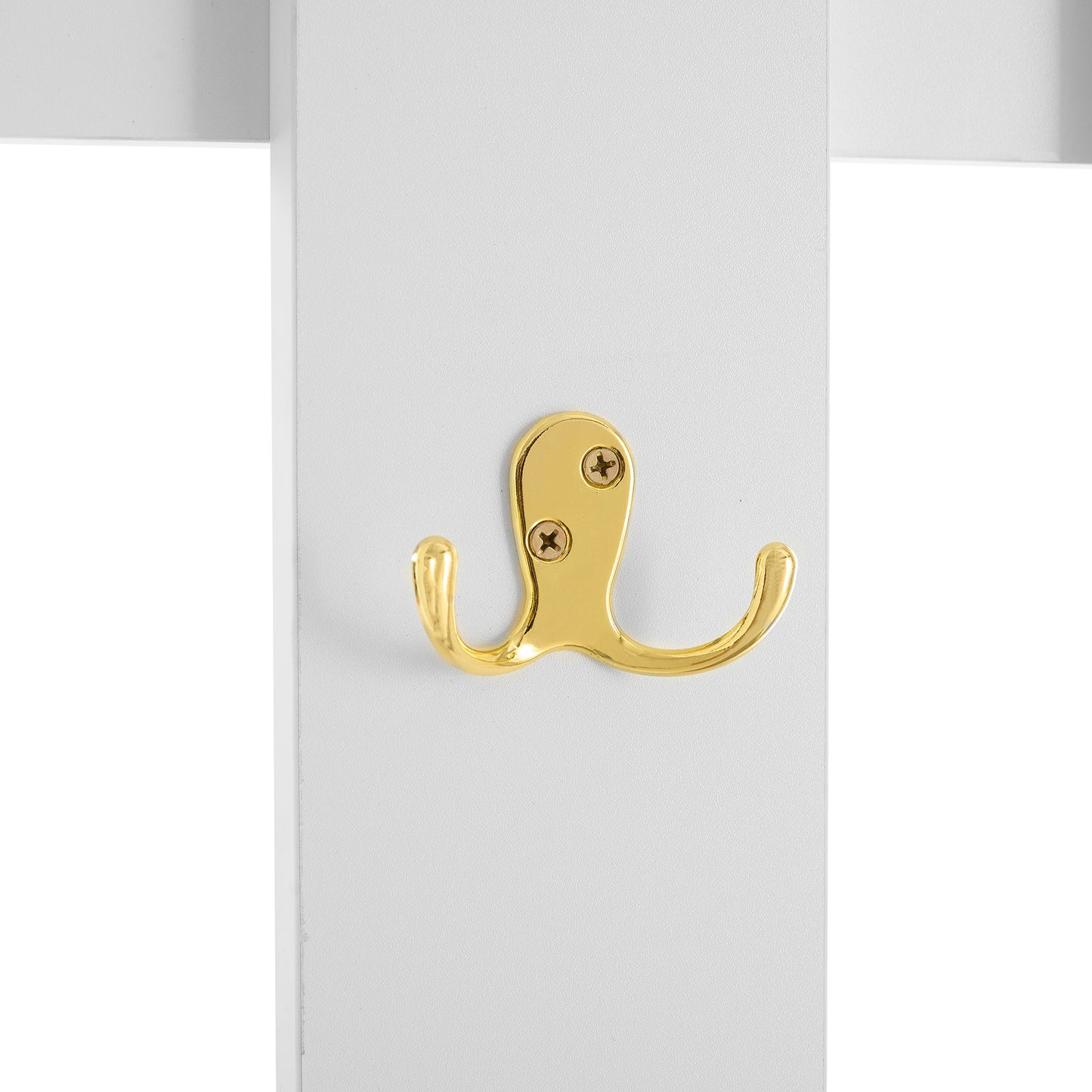Polished brass double hook attached to white board for coat storage