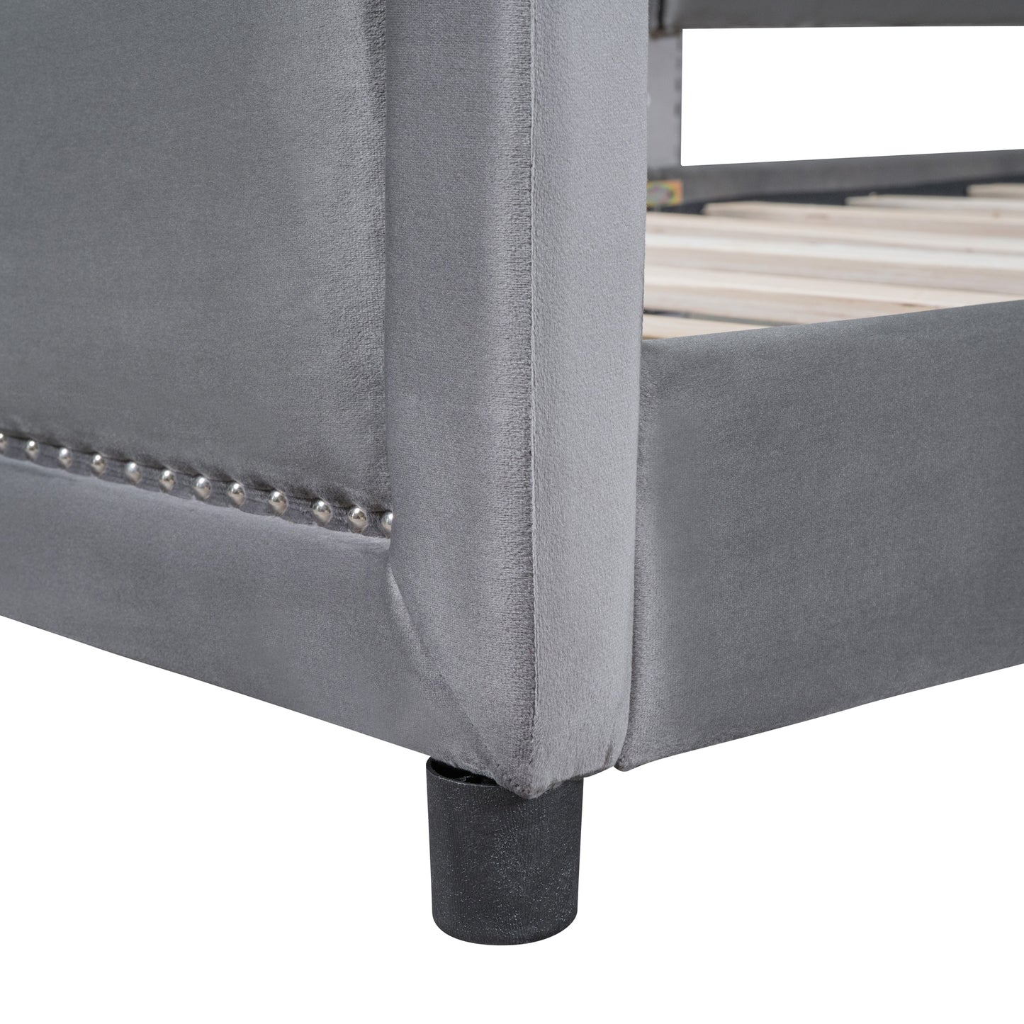 Closeup of grey velvet bed frame with silver stud detailing and a dark cylindrical leg